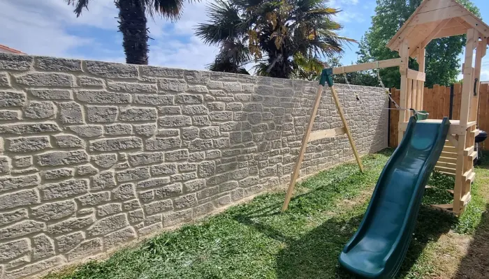 Mur mitoyen en parpaings transformé en enduit imitation pierre